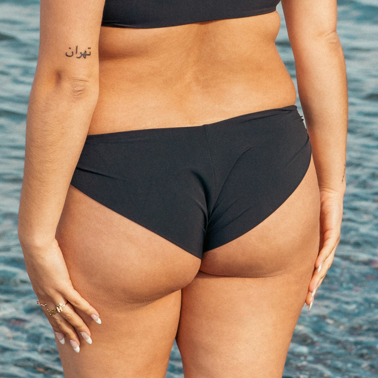 Kvinde i sort cheeky bikinibund på stranden